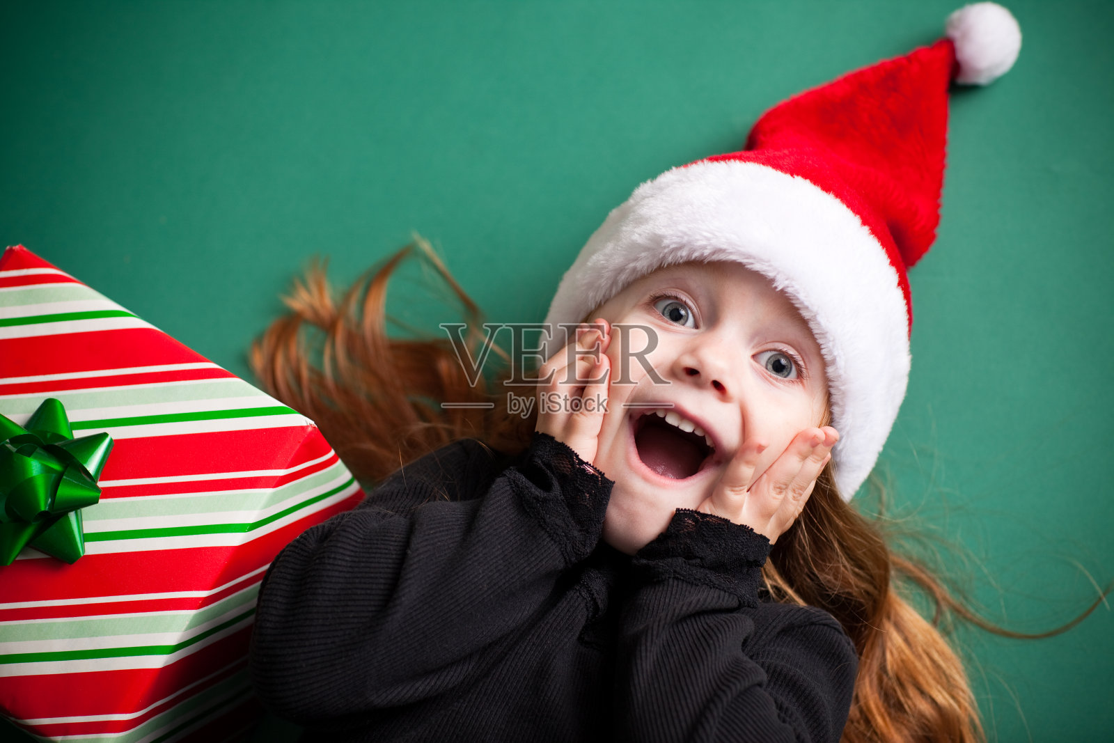 兴奋的女孩戴着圣诞帽与圣诞礼物照片摄影图片