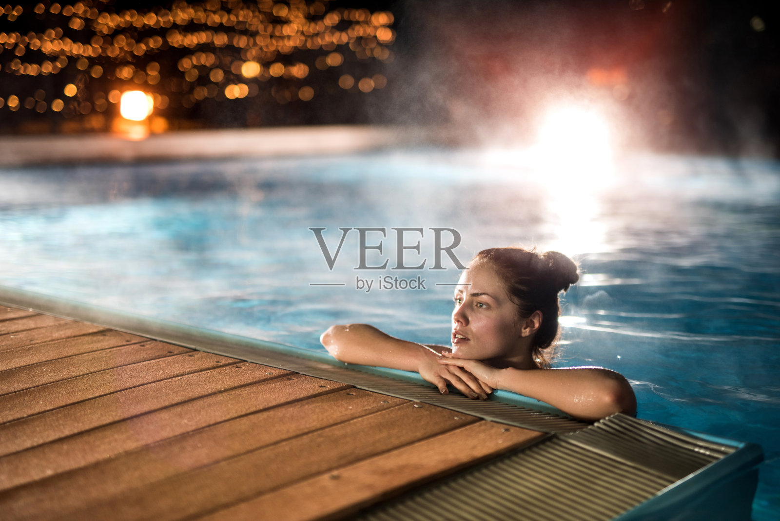 冬夜，年轻女子在热游泳池里放松。照片摄影图片
