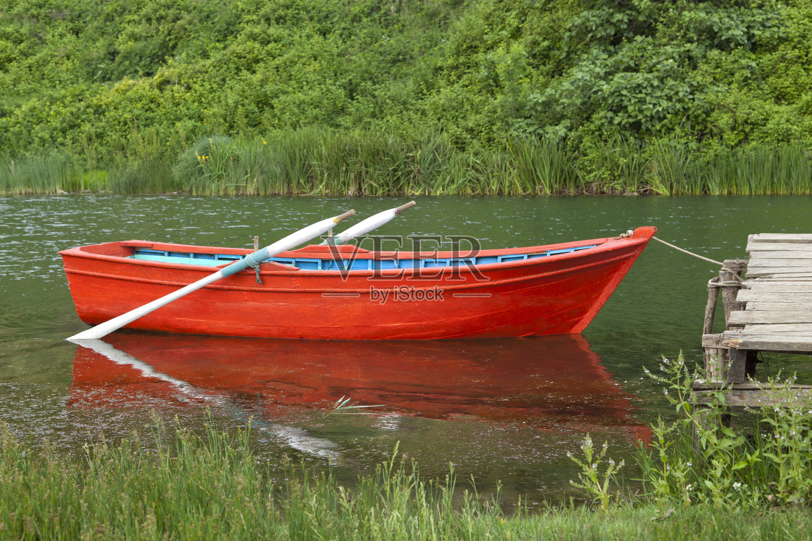 一艘红色的空小船停在湖中照片摄影图片