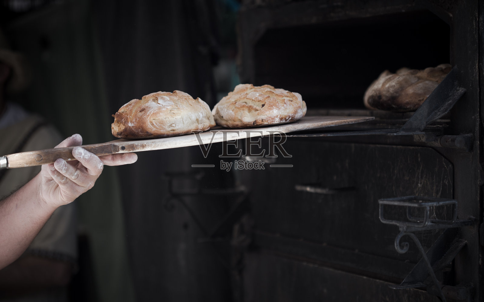 一个男人面包师介绍面包在经典烤箱的特写照片摄影图片