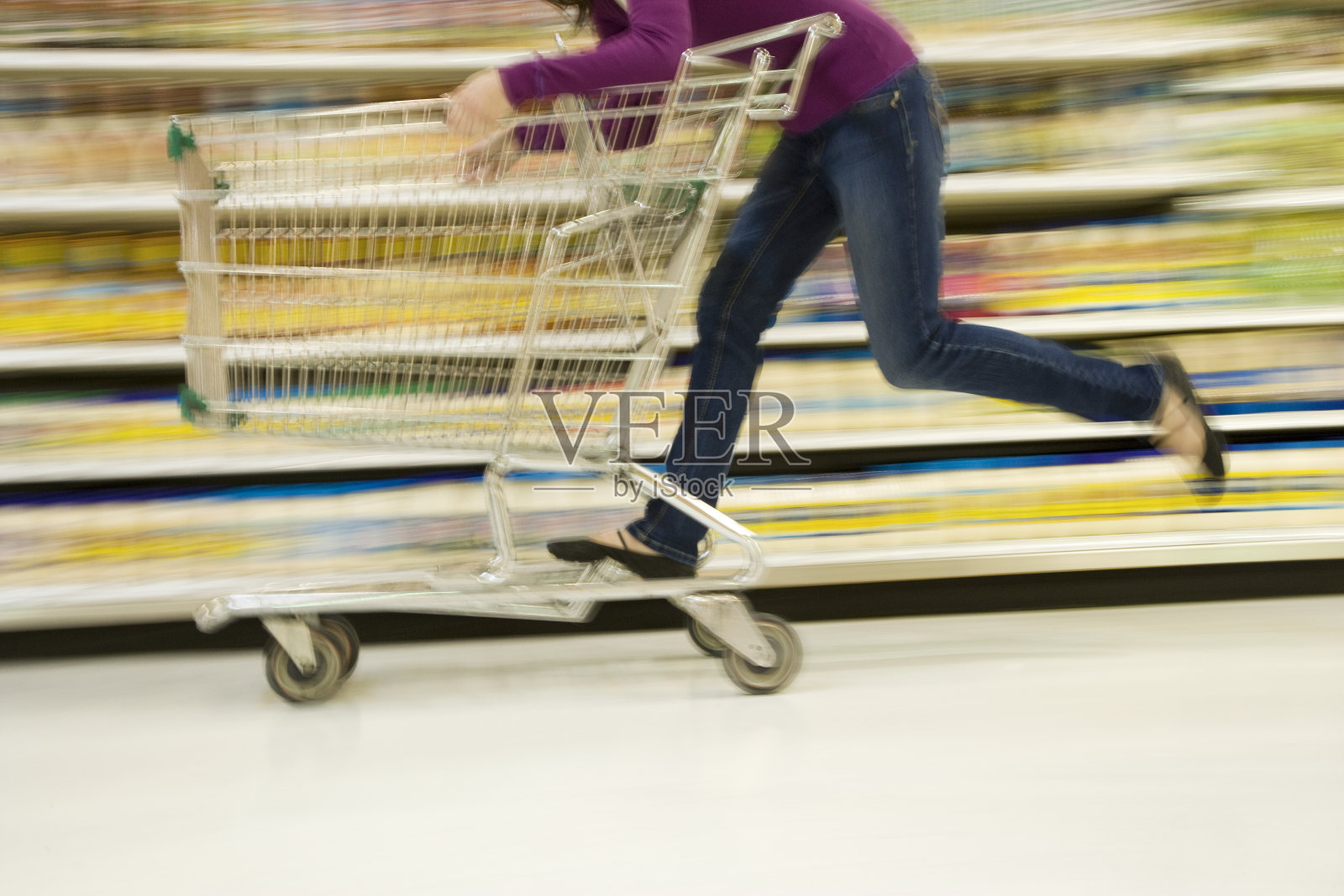 在超市过道上骑着购物车的女人照片摄影图片