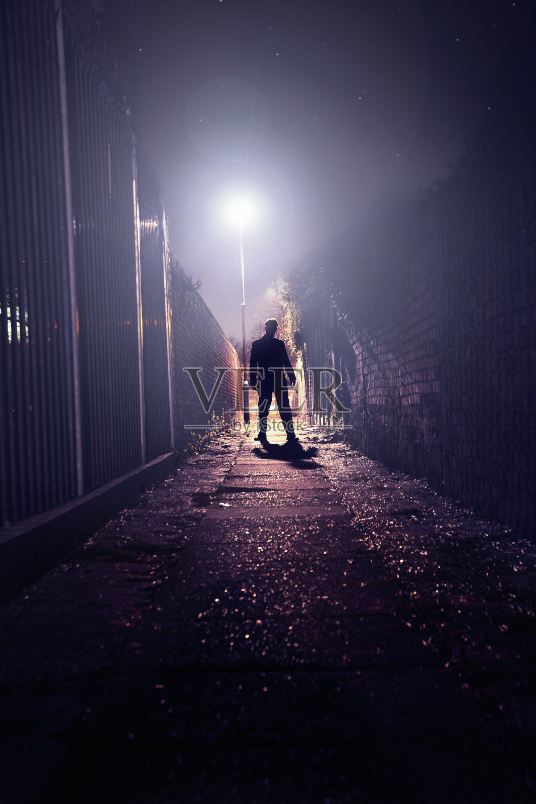 一个人的剪影站在黑暗的巷子里。照片摄影图片
