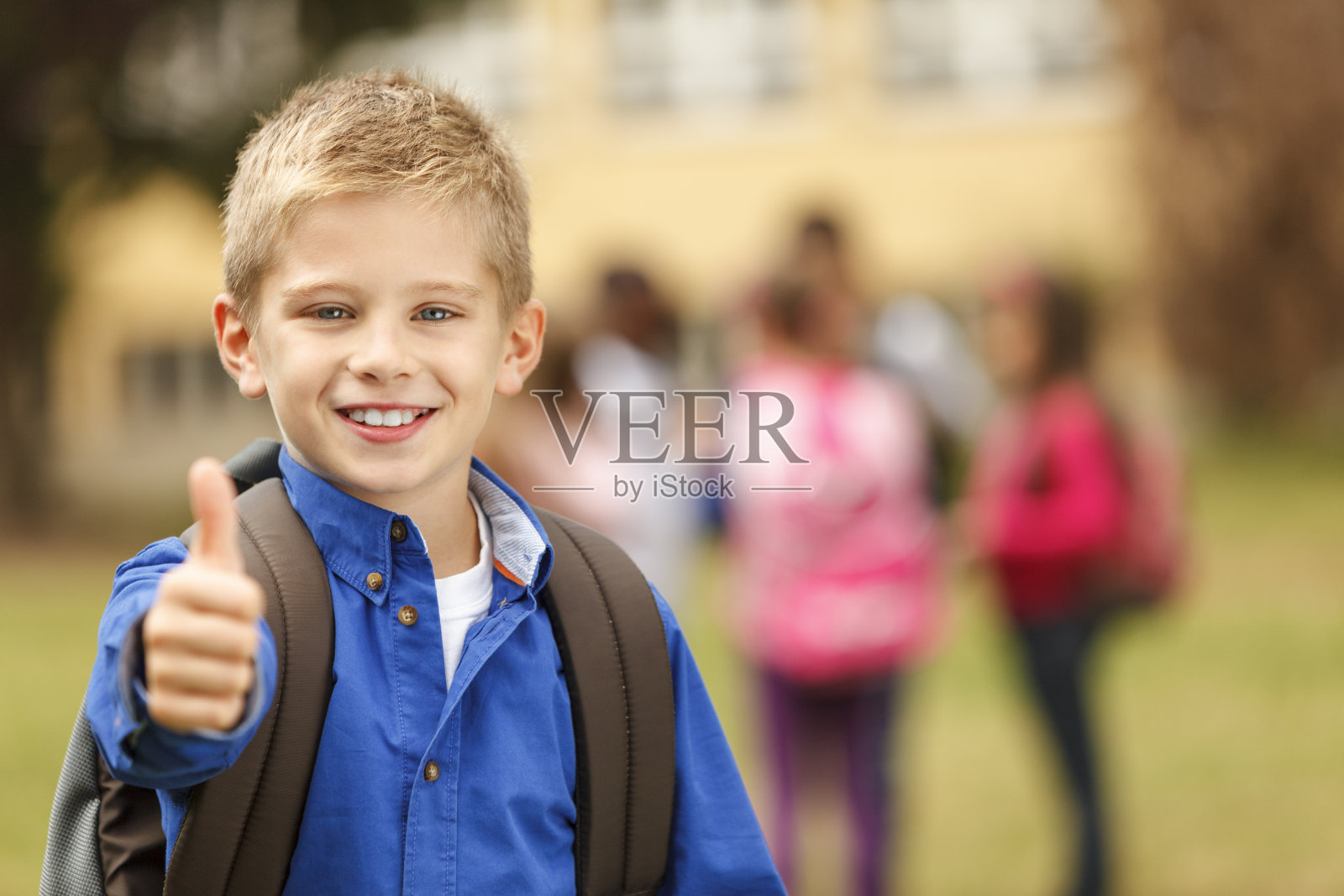 快乐的小男孩在校外竖起大拇指照片摄影图片