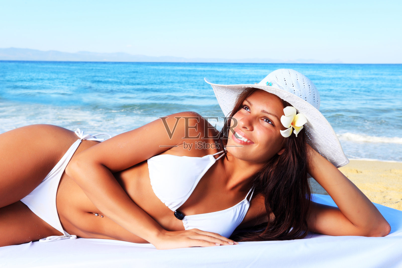 一个美丽女孩的肖像，躺在沙滩上。照片摄影图片