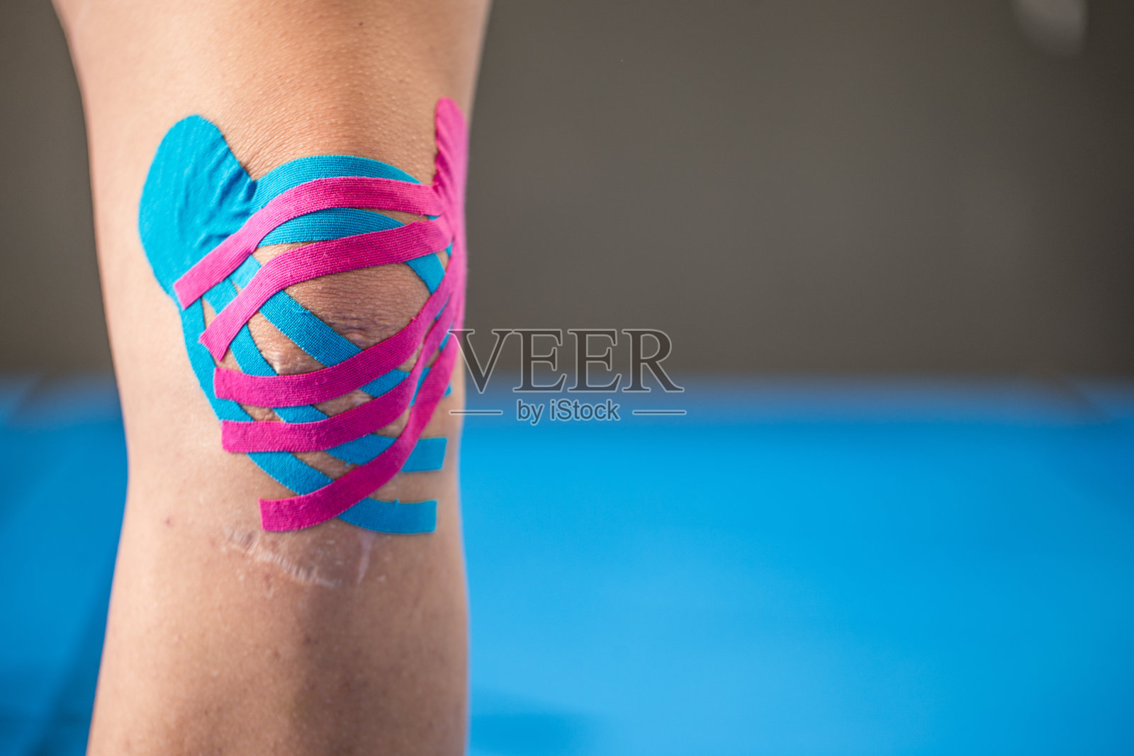 理疗师将运动机能学胶带应用于女性膝盖照片摄影图片