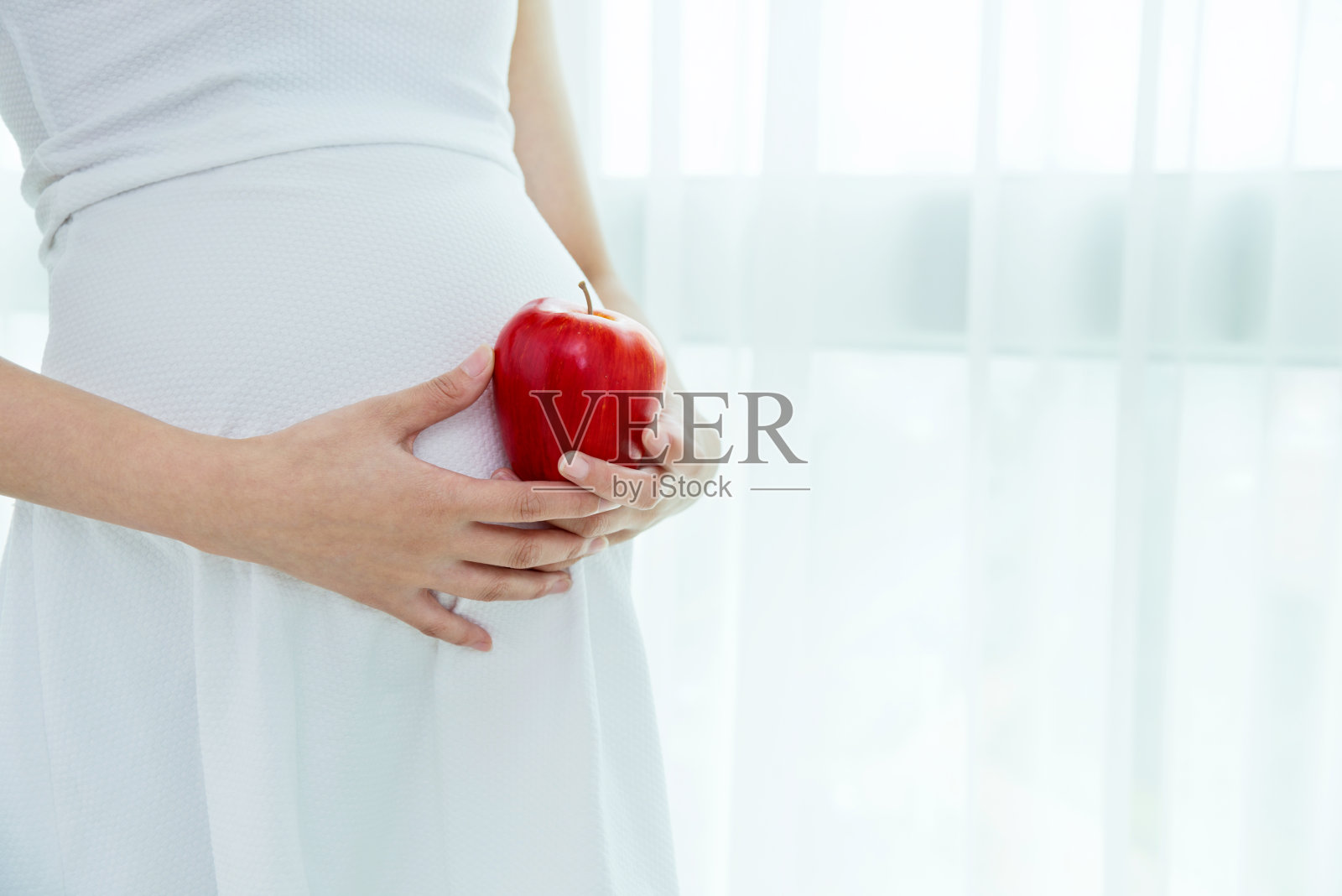 一个孕妇拿着一个红苹果照片摄影图片