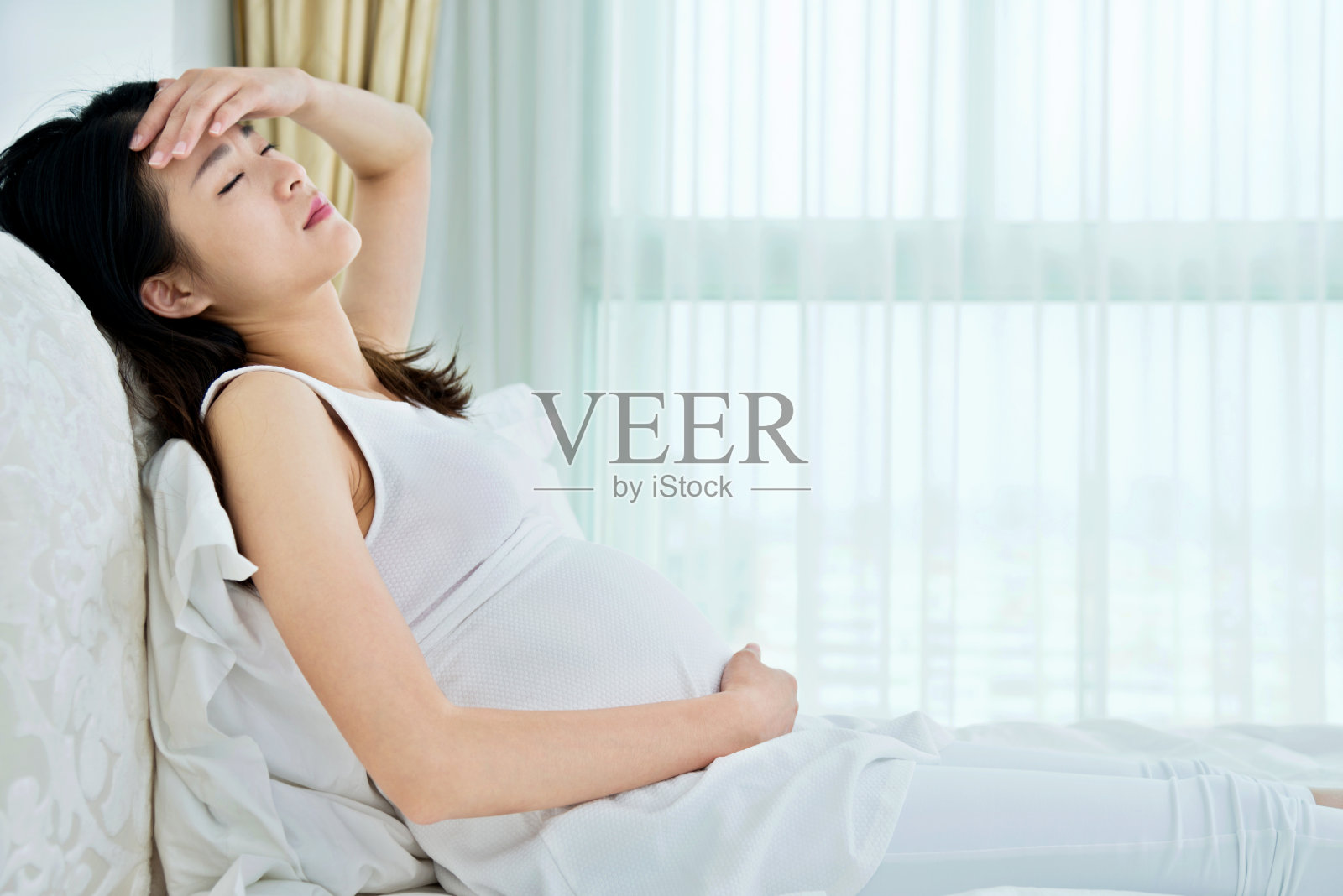 一个孕妇坐在床上照片摄影图片