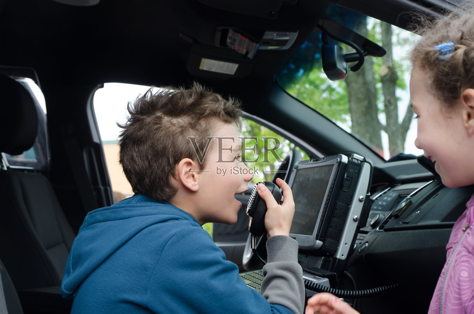 小男孩在警车里玩警察无线电照片摄影图片