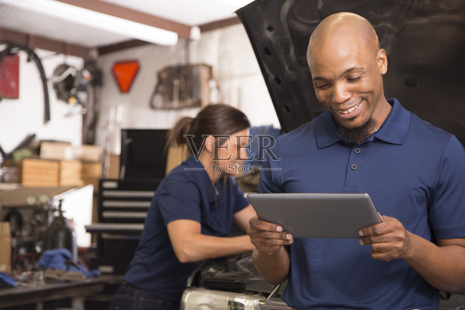 男，女机械师一起在汽车修理厂工作。照片摄影图片