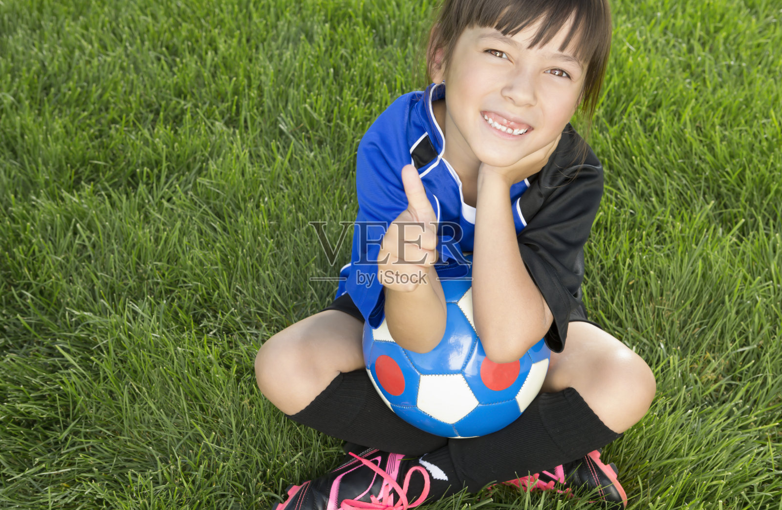 小女孩在足球场上竖起大拇指照片摄影图片