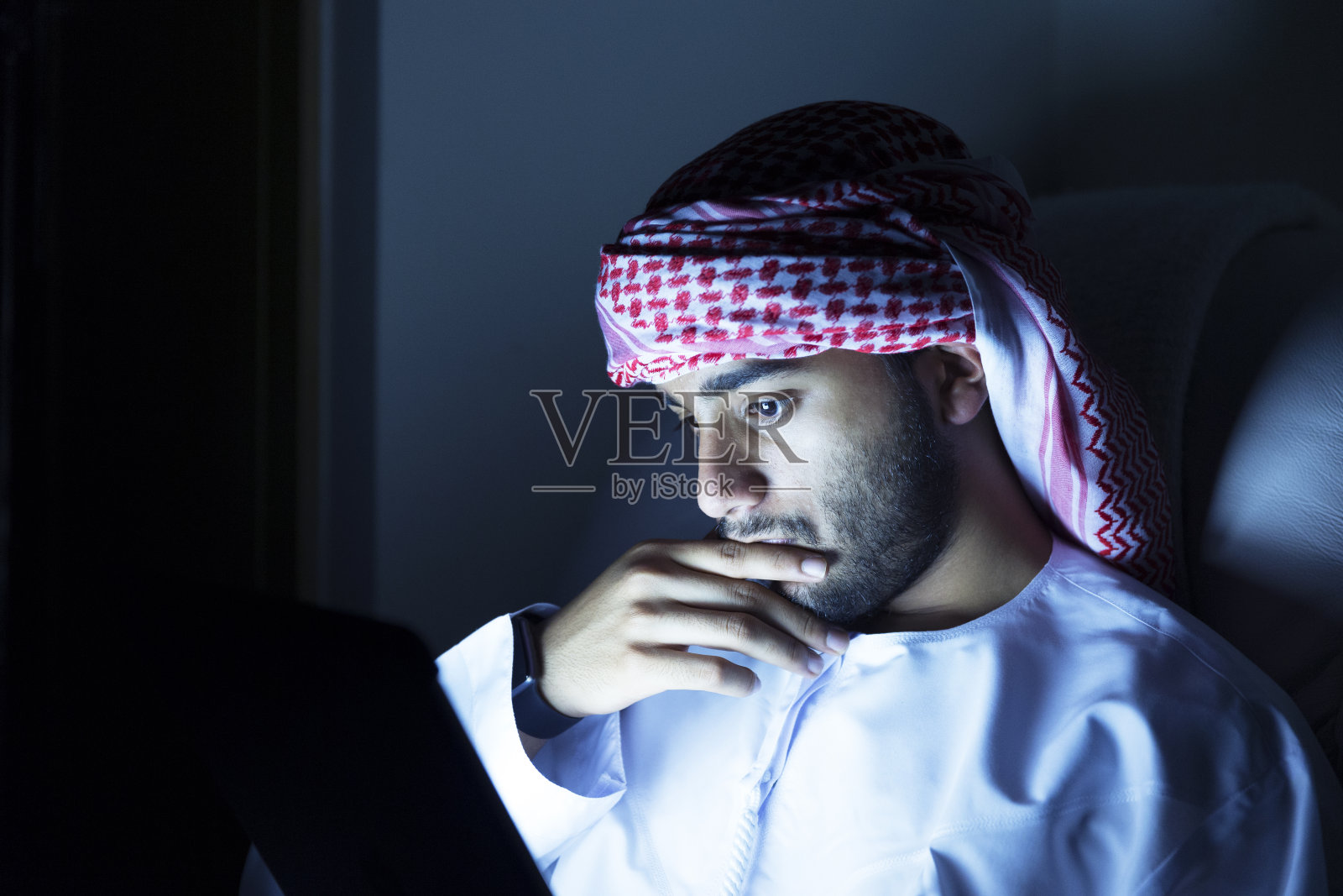 年轻的阿拉伯少年在他的数字平板电脑上阅读照片摄影图片