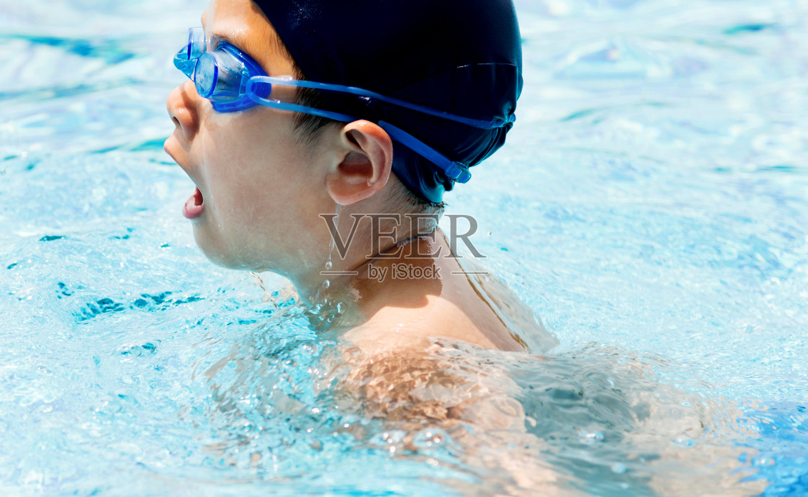 小男孩在游泳池里游泳照片摄影图片