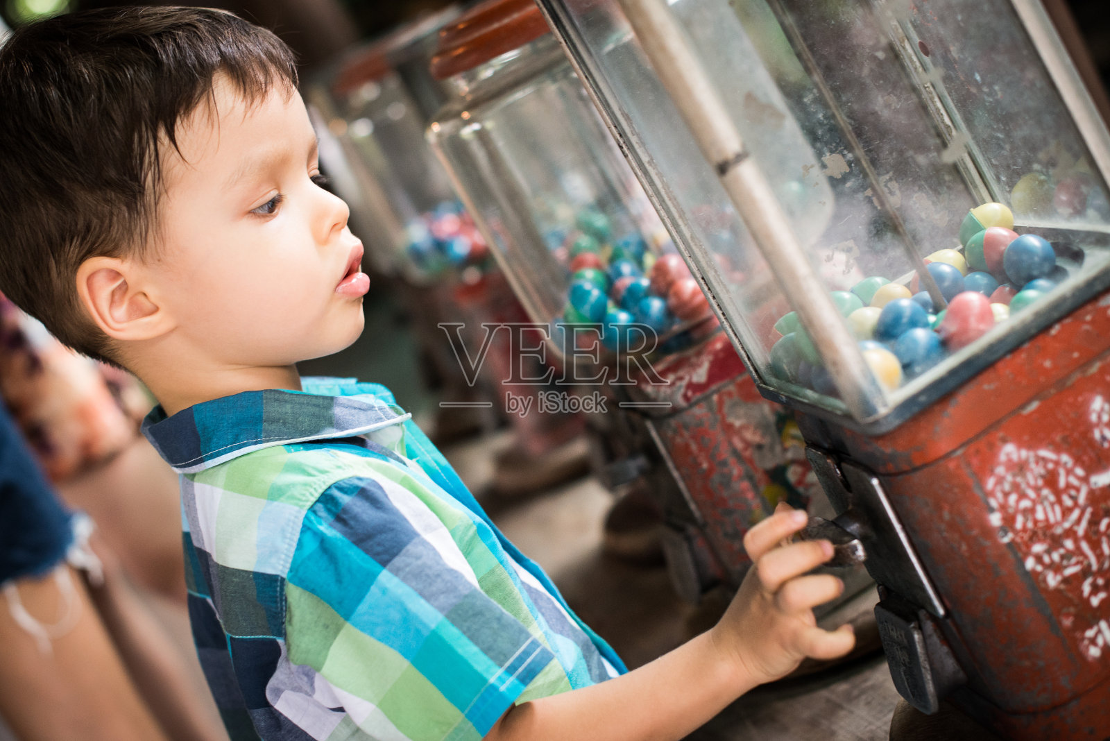蹒跚学步的孩子从古董贩卖机里拿玩具照片摄影图片