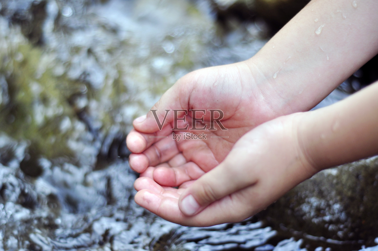 孩子用手在河里舀清水照片摄影图片
