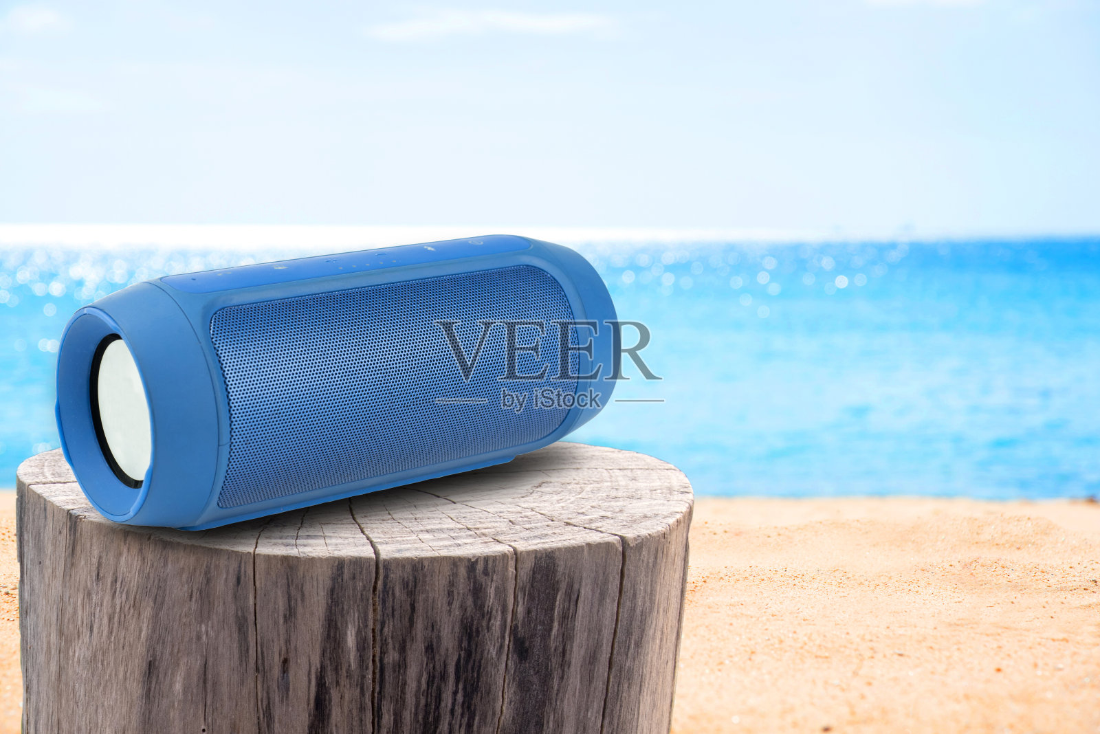 便携式扬声器在Stump桌子和沙滩上。照片摄影图片