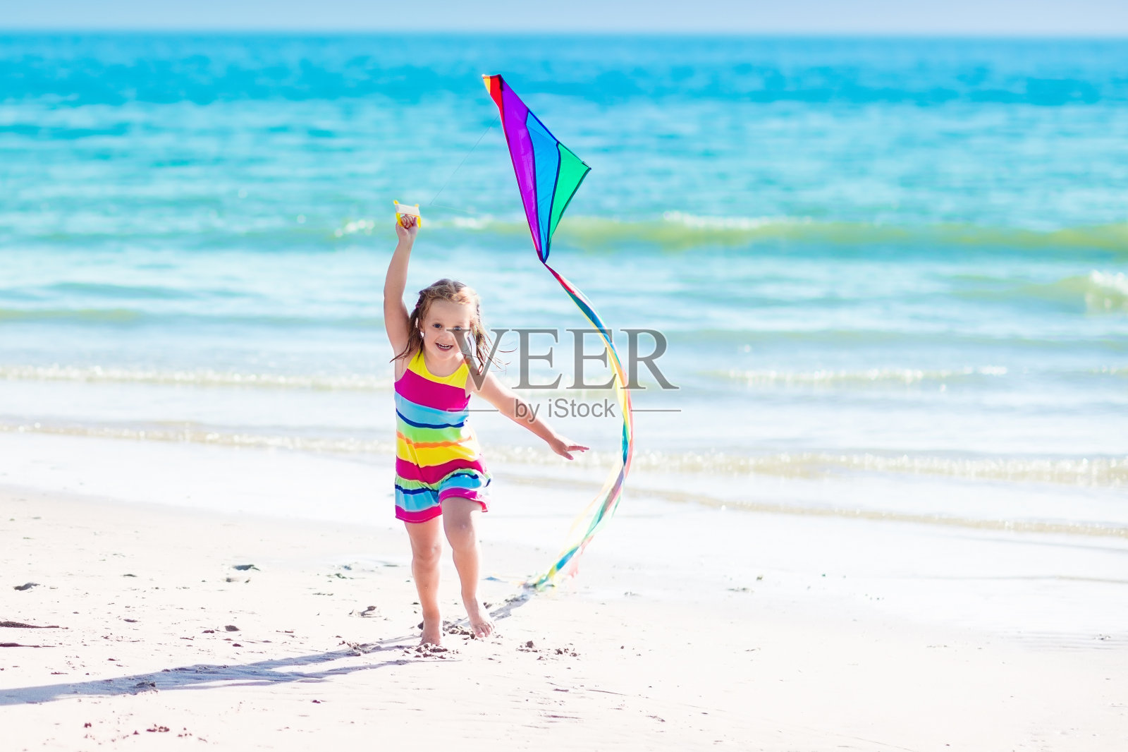 孩子在热带海滩上放风筝照片摄影图片