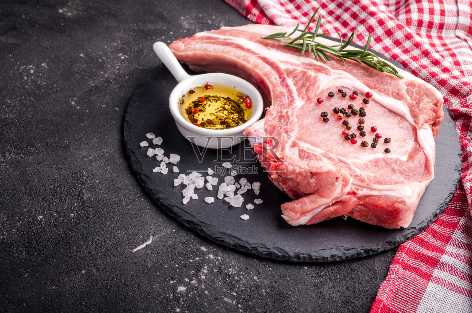 生肉与香草，油和香料在黑暗的背景。生猪肉牛排。烹饪肉类的配料照片摄影图片