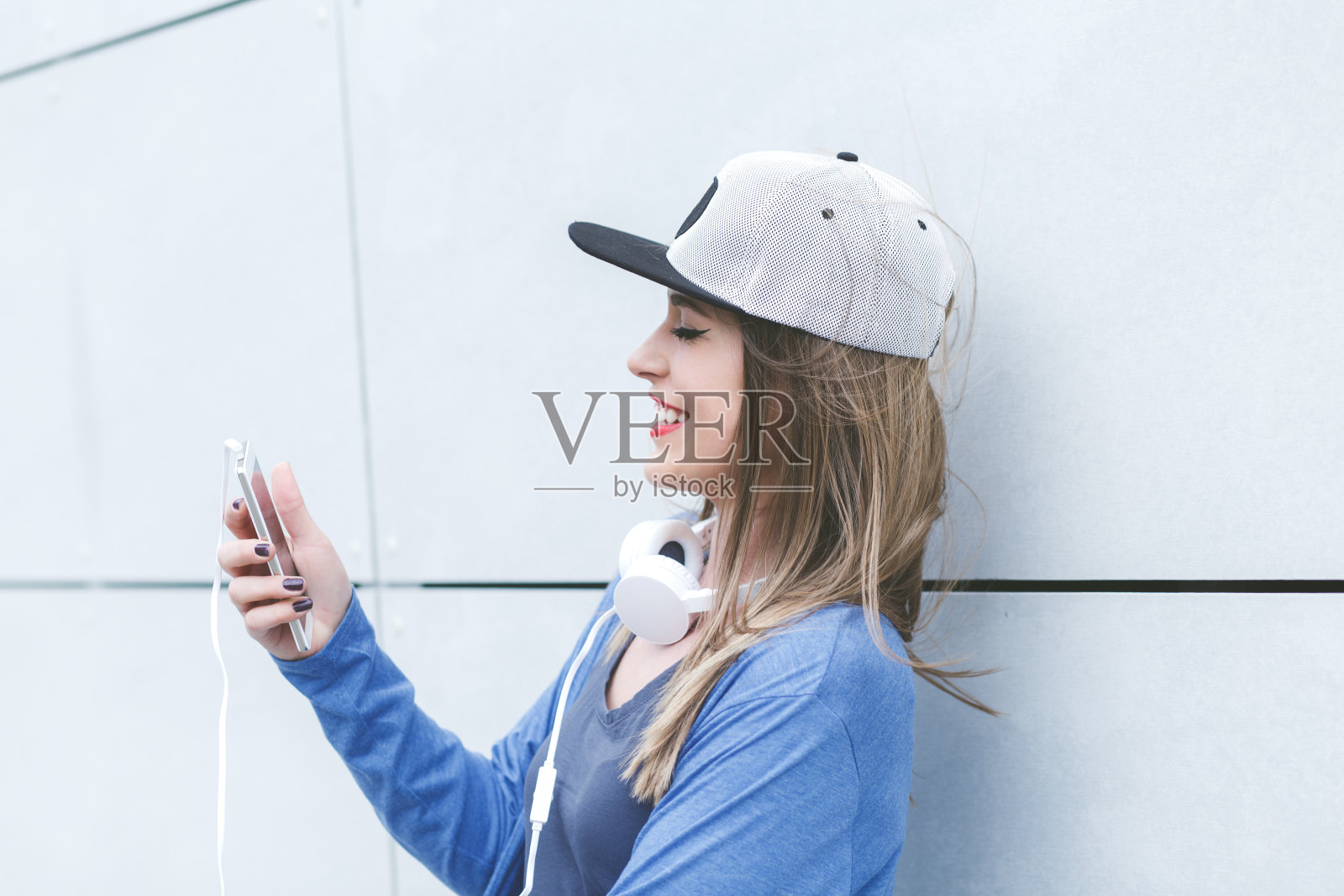 年轻女子的肖像戴着耳机和手机。照片摄影图片