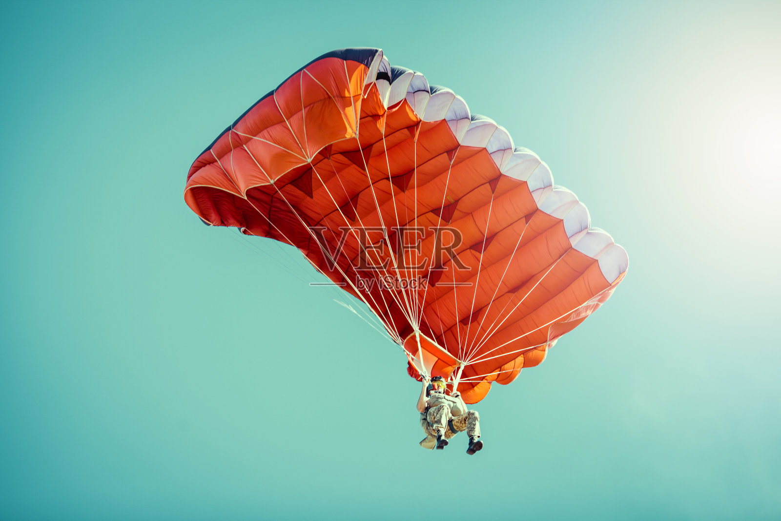 在晴朗晴朗的天空中乘坐彩色降落伞的跳伞者。照片摄影图片