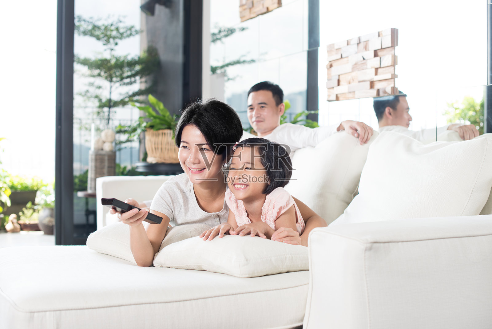 年轻的亚洲家庭在家里看电视。照片摄影图片