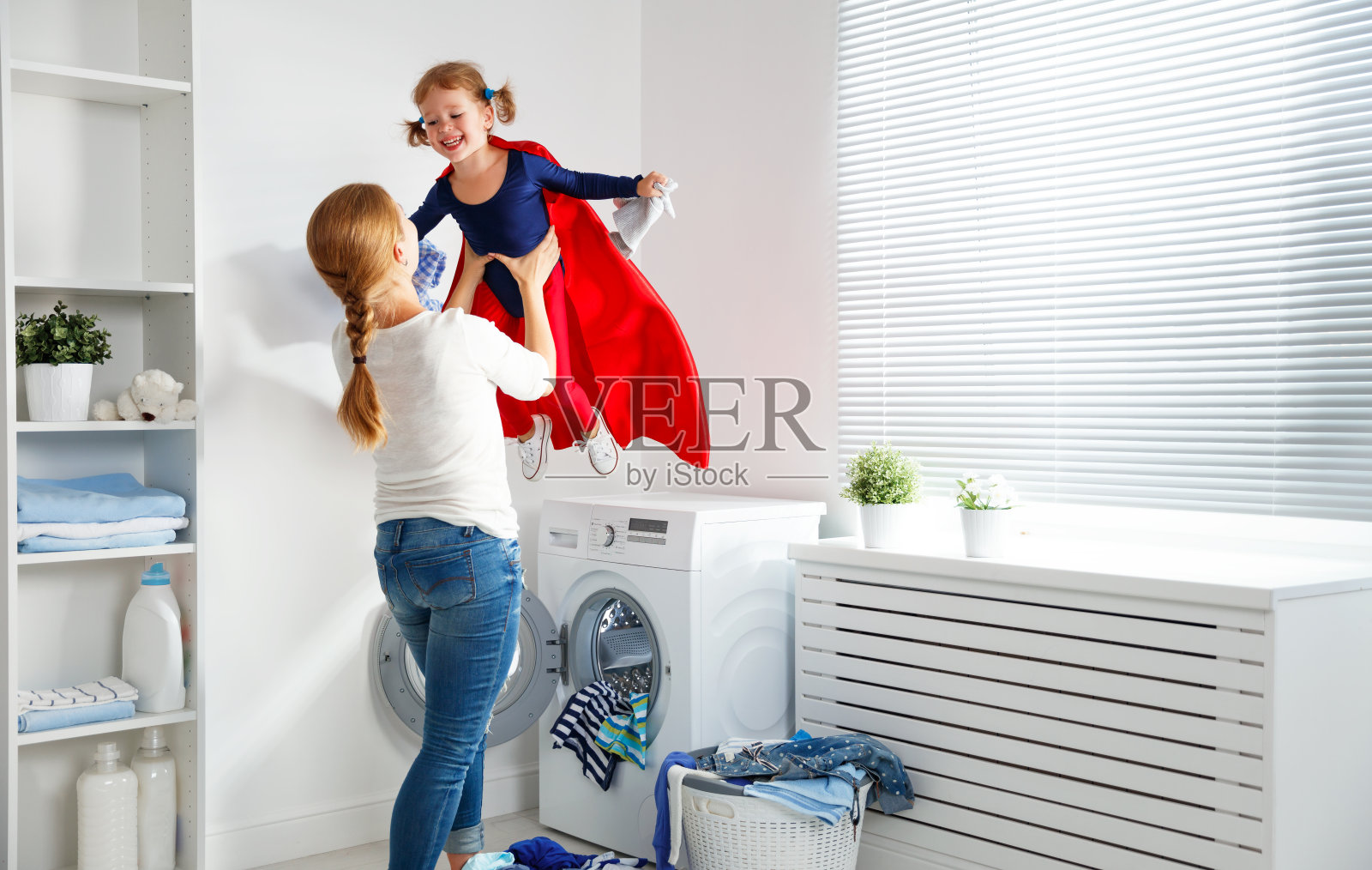 家庭妈妈和孩子女孩小超级英雄助手在洗衣照片摄影图片