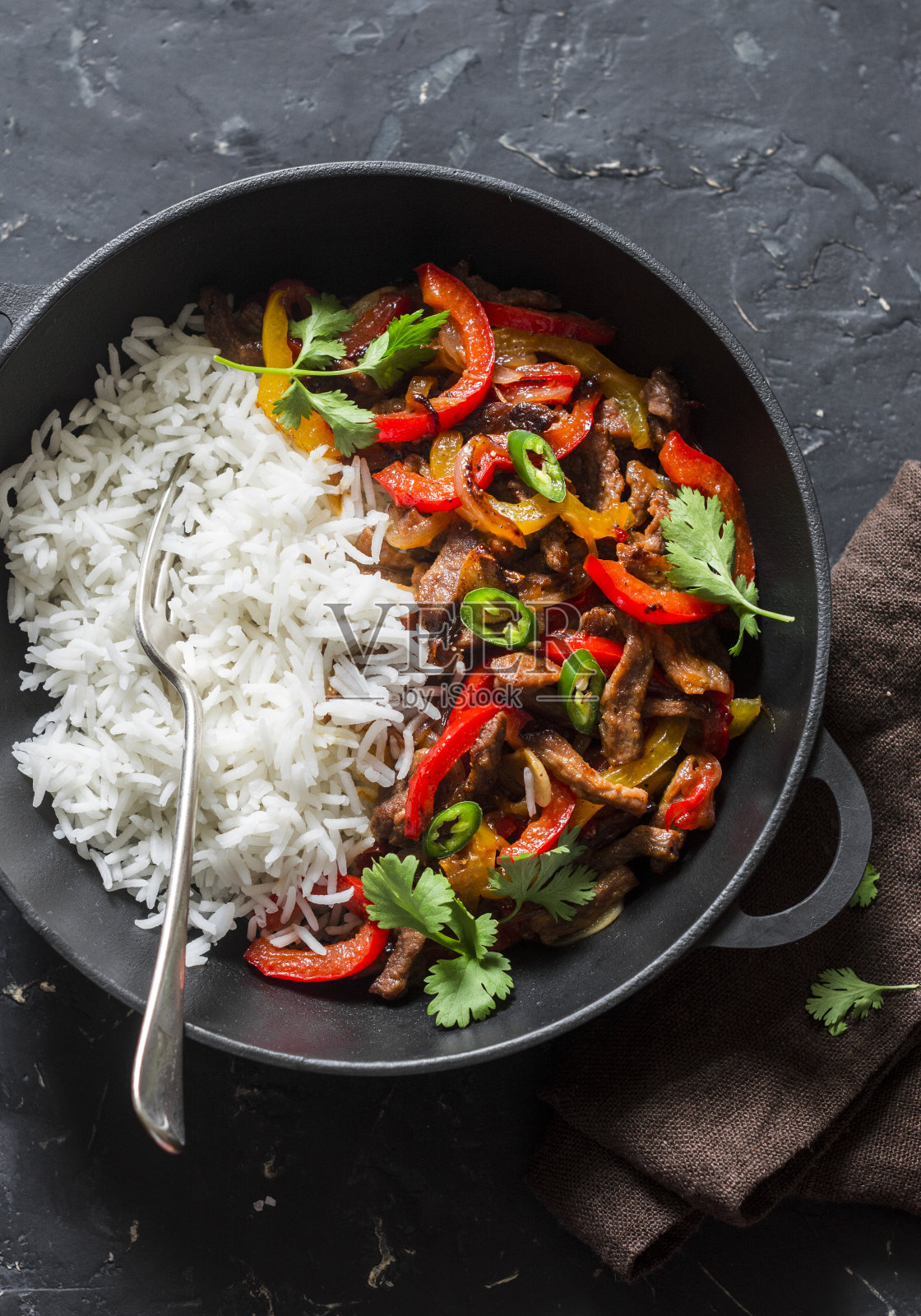 辣牛肉，蔬菜和米饭在一个铸铁锅在黑暗的背景，俯视图。亚洲风格的食物照片摄影图片