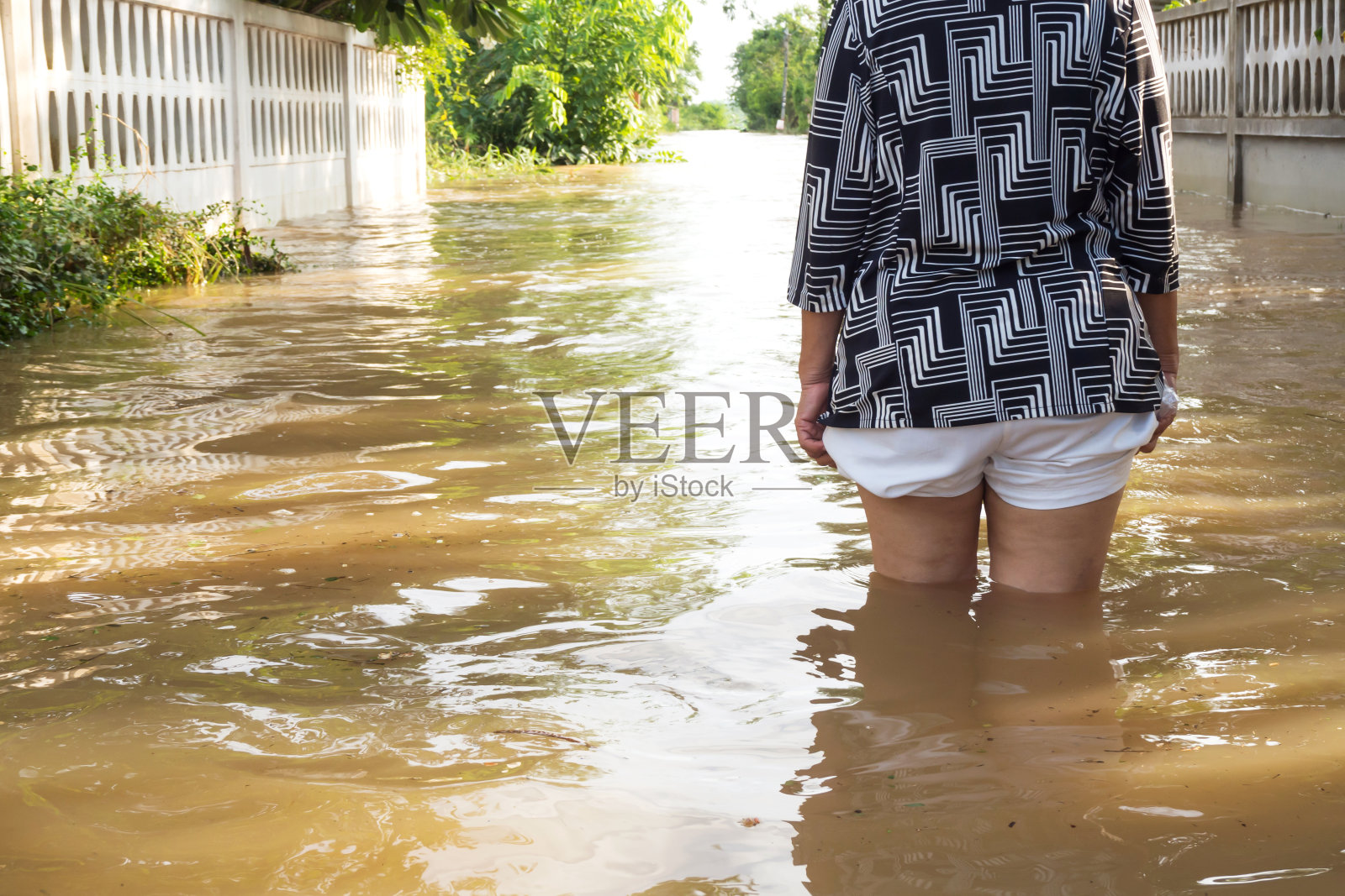 《洪水》中的女人的背影。洪水的房子。她的腿的特写。照片摄影图片