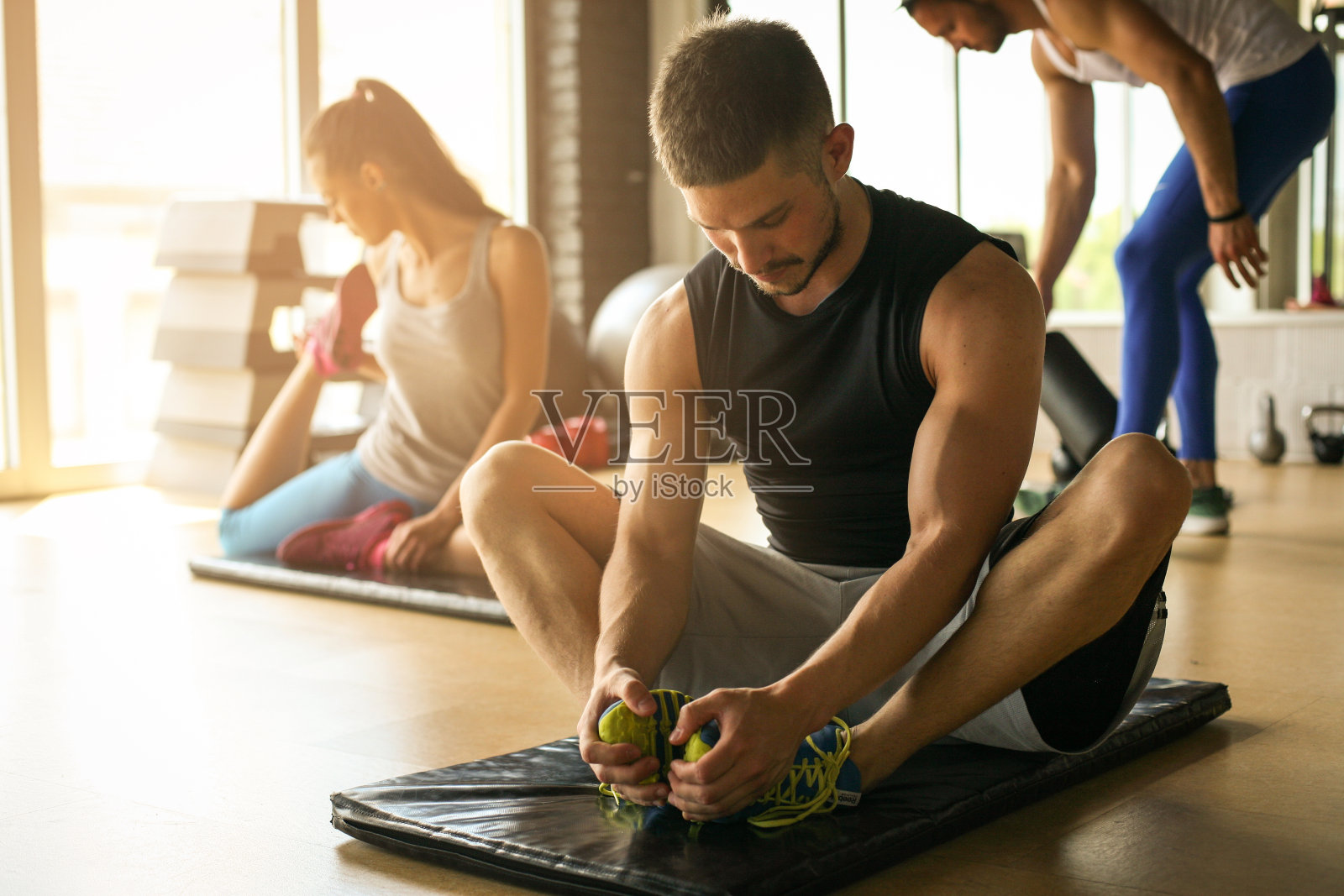 一群人在健康俱乐部锻炼。年轻人在地板上伸展身体。照片摄影图片