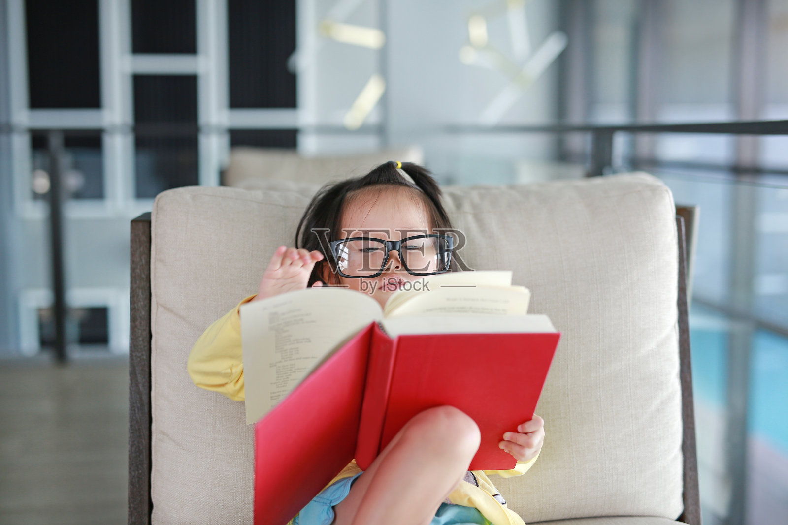 带眼镜的小女孩在图书馆看书，教育理念。照片摄影图片