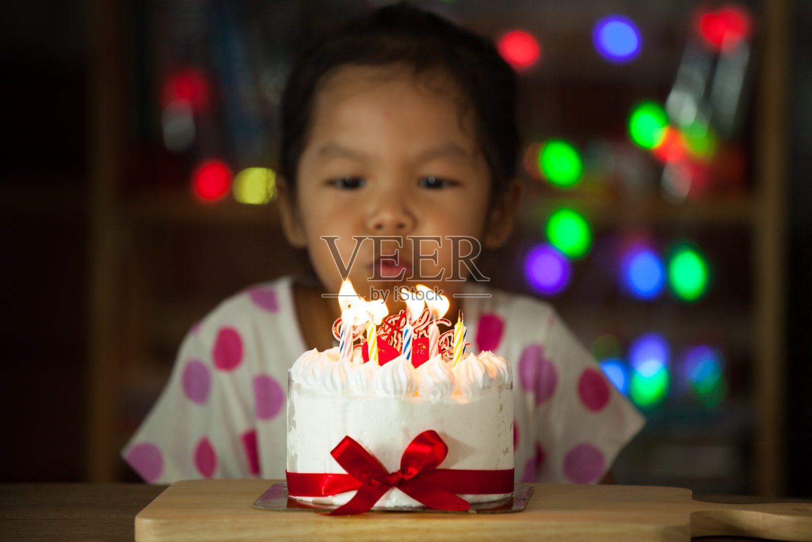 可爱的亚洲小女孩庆祝生日和吹蜡烛的生日蛋糕照片摄影图片