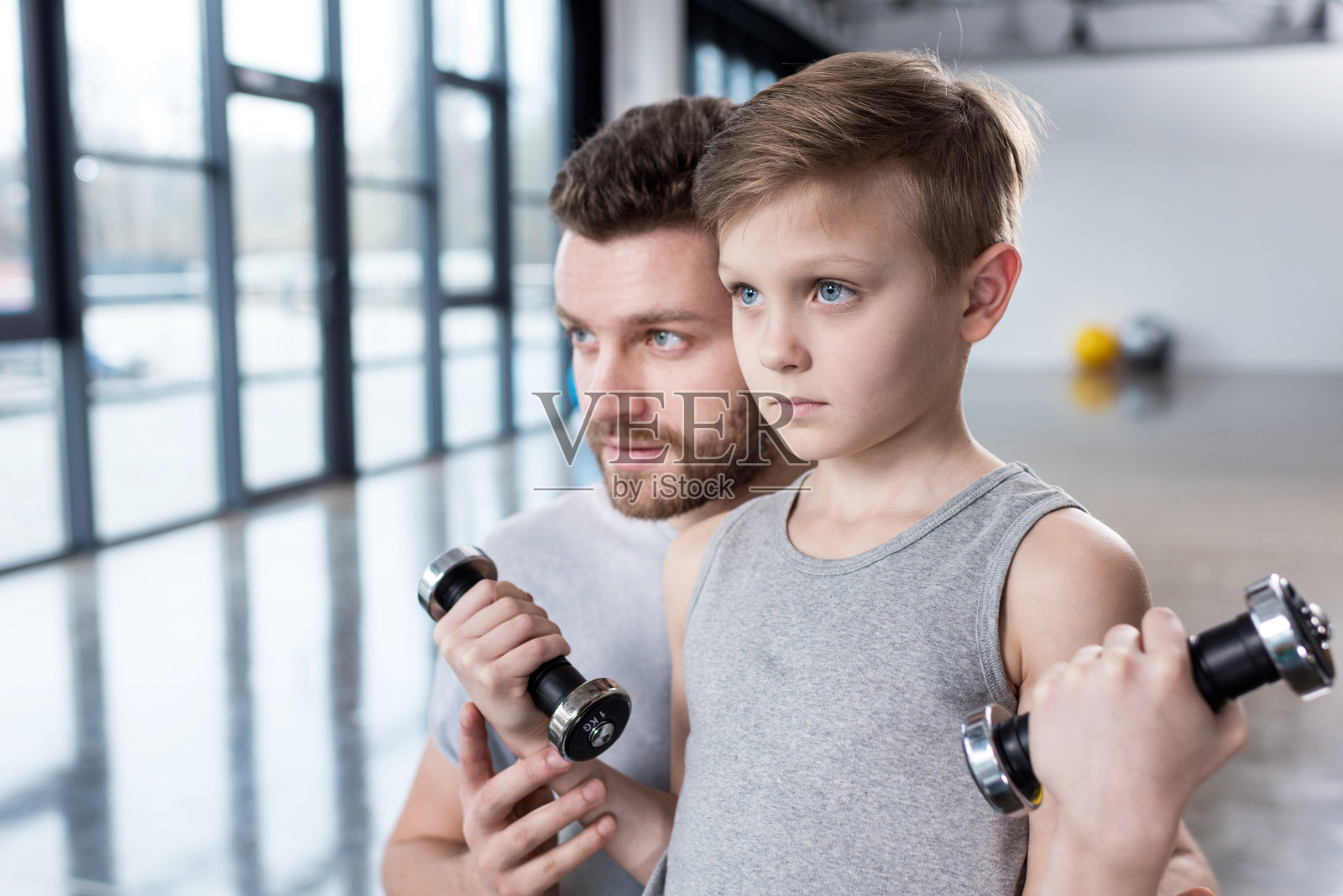 男孩在健身中心和教练一起用哑铃训练照片摄影图片