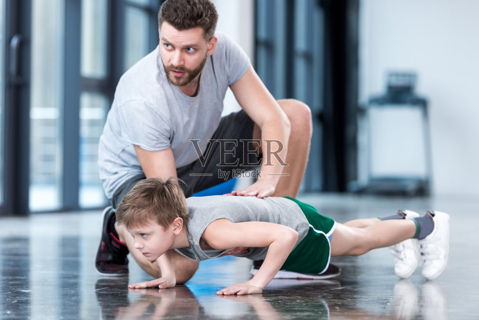 男孩在健身中心和教练做俯卧撑照片摄影图片