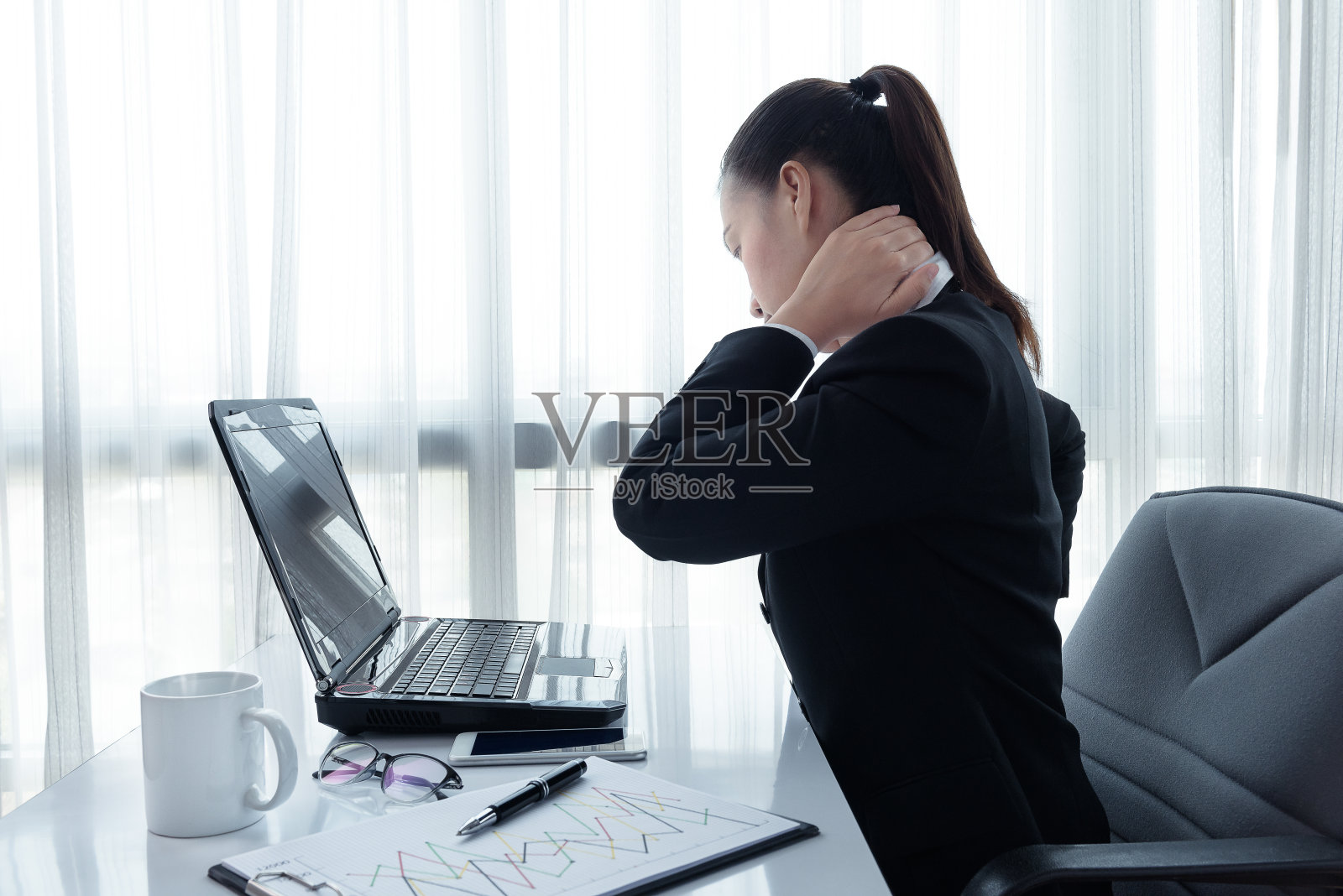 一名压力重重的年轻女性坐在办公桌前的笔记本电脑前的肖像照片摄影图片
