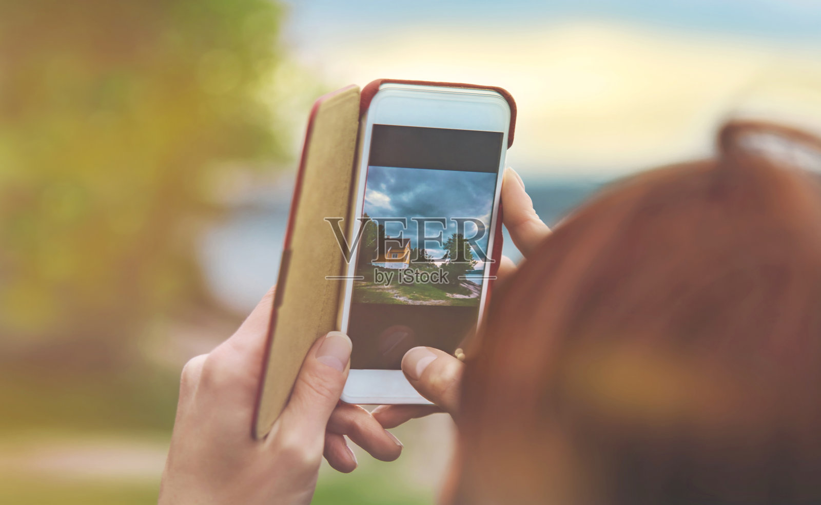 日落时分，挪威的女性手拿着智能手机拍摄风景照片摄影图片