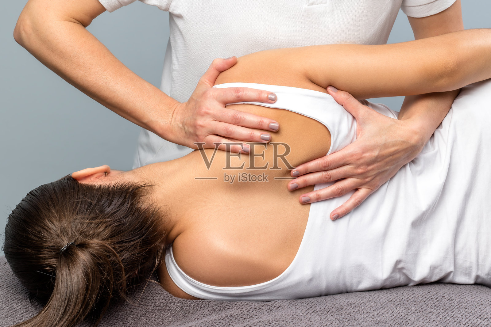 女性治疗师操作患者肩胛骨的细节。照片摄影图片