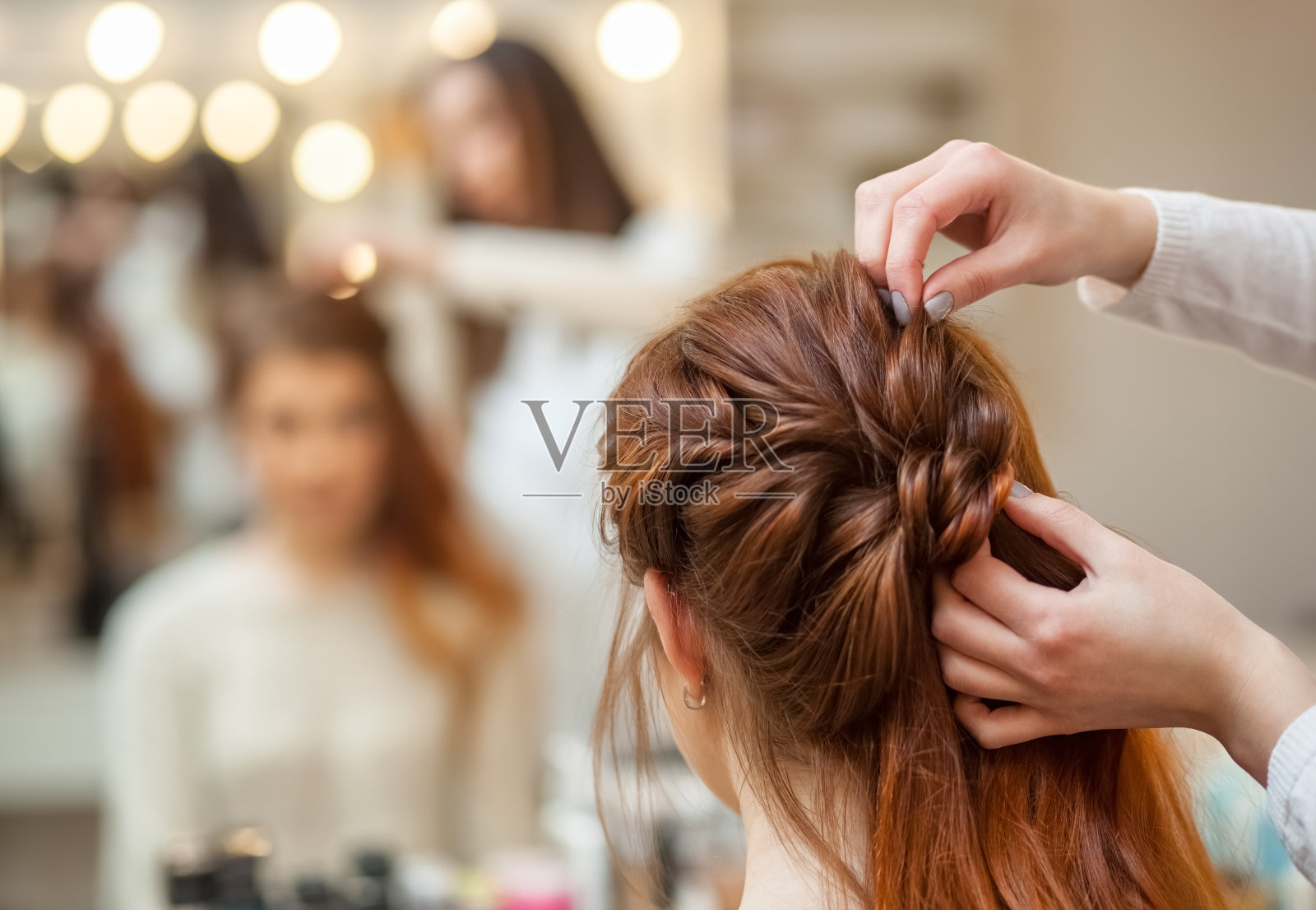 一个漂亮的长头发的红发女孩，美发师编了一个法式辫子，在美容院照片摄影图片