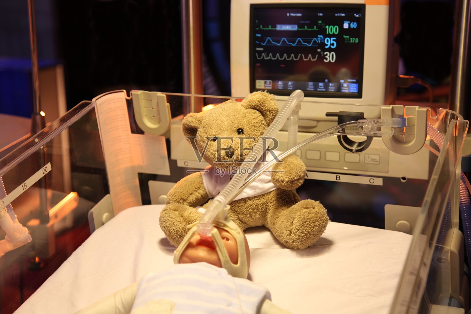 保温箱里的娃娃。新出生的。呼吸机。泰迪熊照片摄影图片