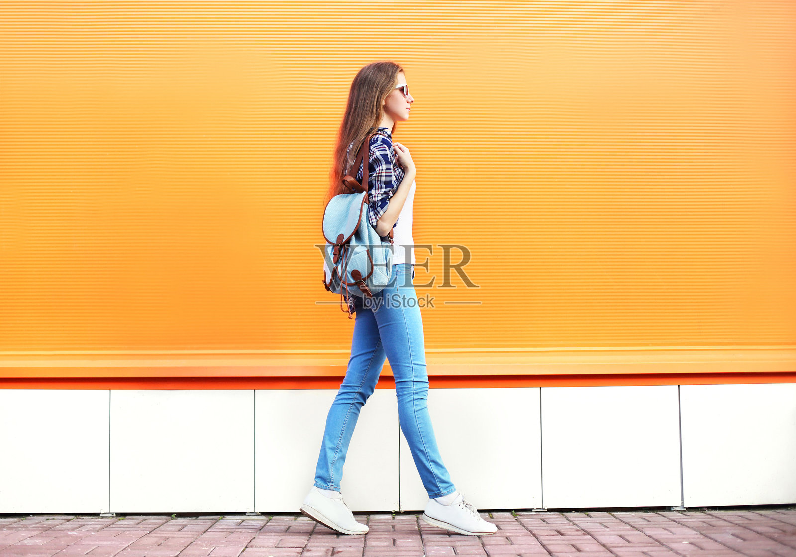 时尚的女人走在五颜六色的橙色背景的城市照片摄影图片