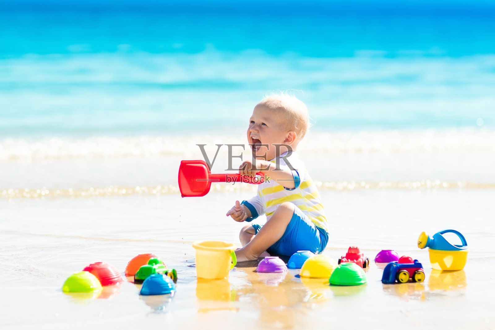 宝宝在热带海滩上玩，在沙子里挖洞照片摄影图片