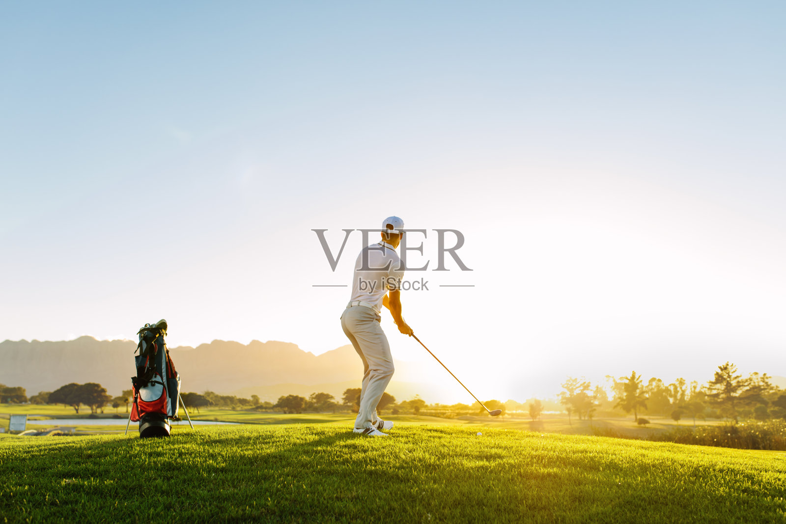 在高尔夫球场上击球的职业男性高尔夫球手照片摄影图片