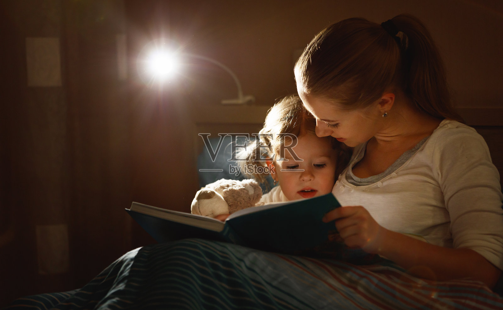 睡觉前妈妈和孩子在床上看书照片摄影图片