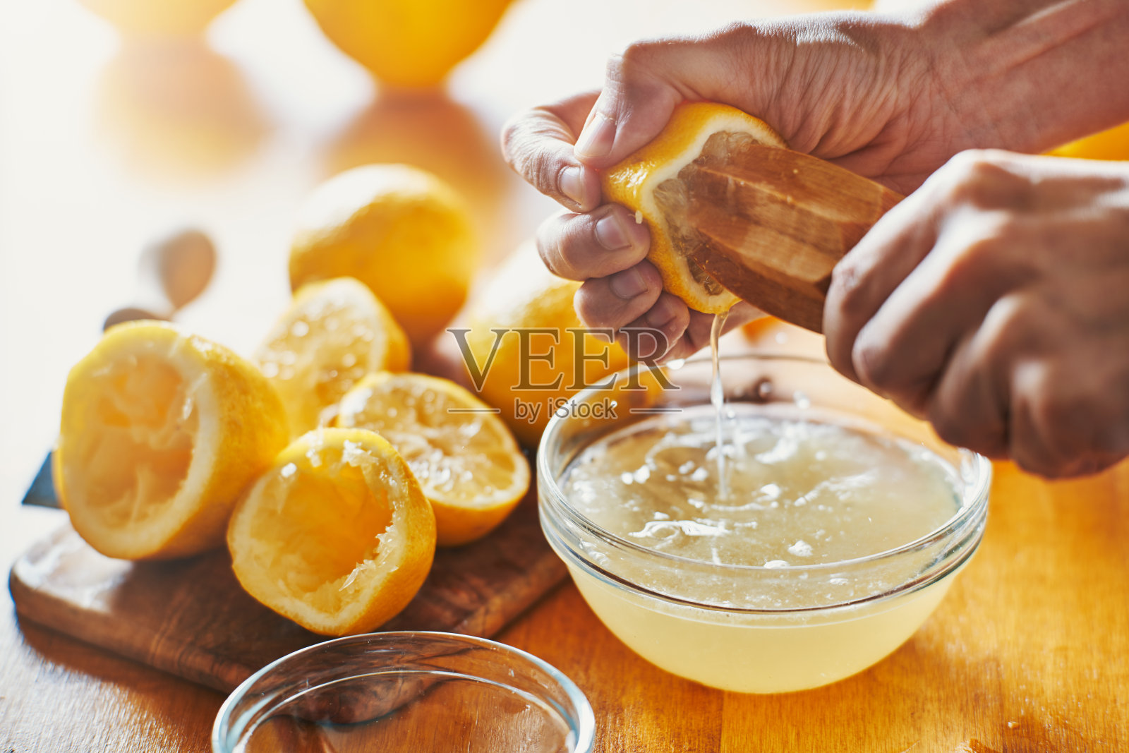 女人的手用木制工具从柠檬中挤出汁照片摄影图片