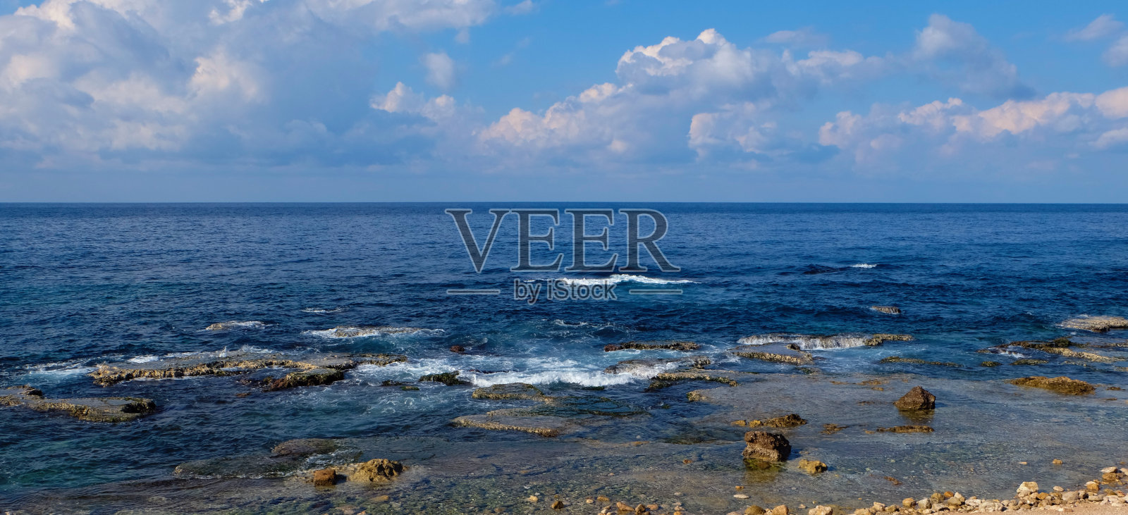 海景全景-在海岸的自然岩层和清澈的蓝色的水与光波到地平线照片摄影图片