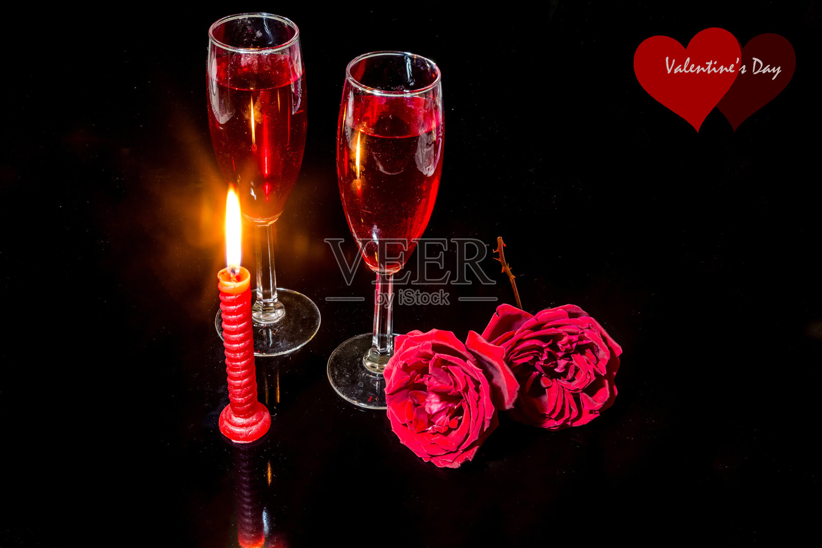 烛光、红玫瑰、红酒杯，映衬着黑暗的背景，营造出浪漫的氛围。照片摄影图片
