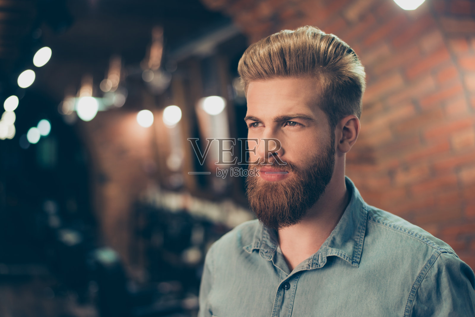 一个令人惊叹的红色胡子的男人在理发店时髦的发型的特写。看起来如此时尚和自信照片摄影图片