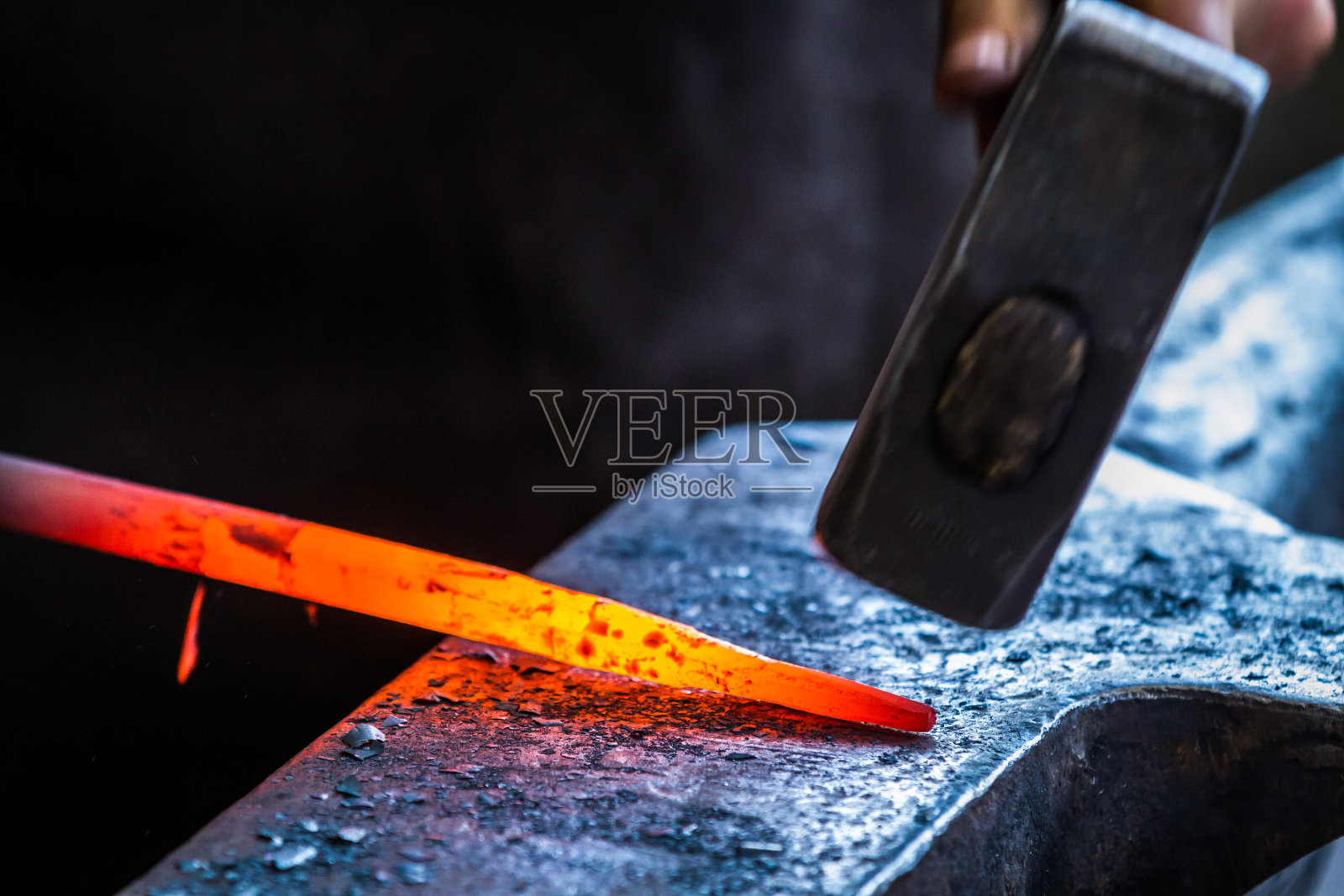 铁匠的锤子，在铁砧上敲击加热的金属棒照片摄影图片