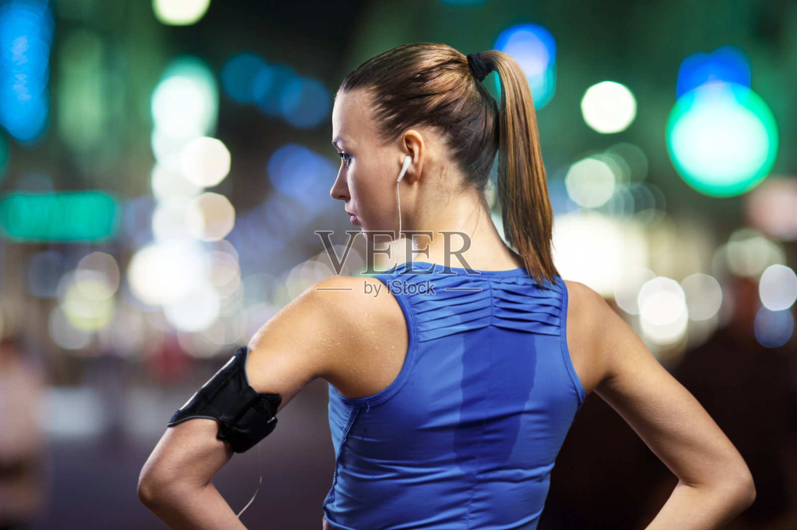 运动女性慢跑穿过夜晚灯火通明的城市照片摄影图片