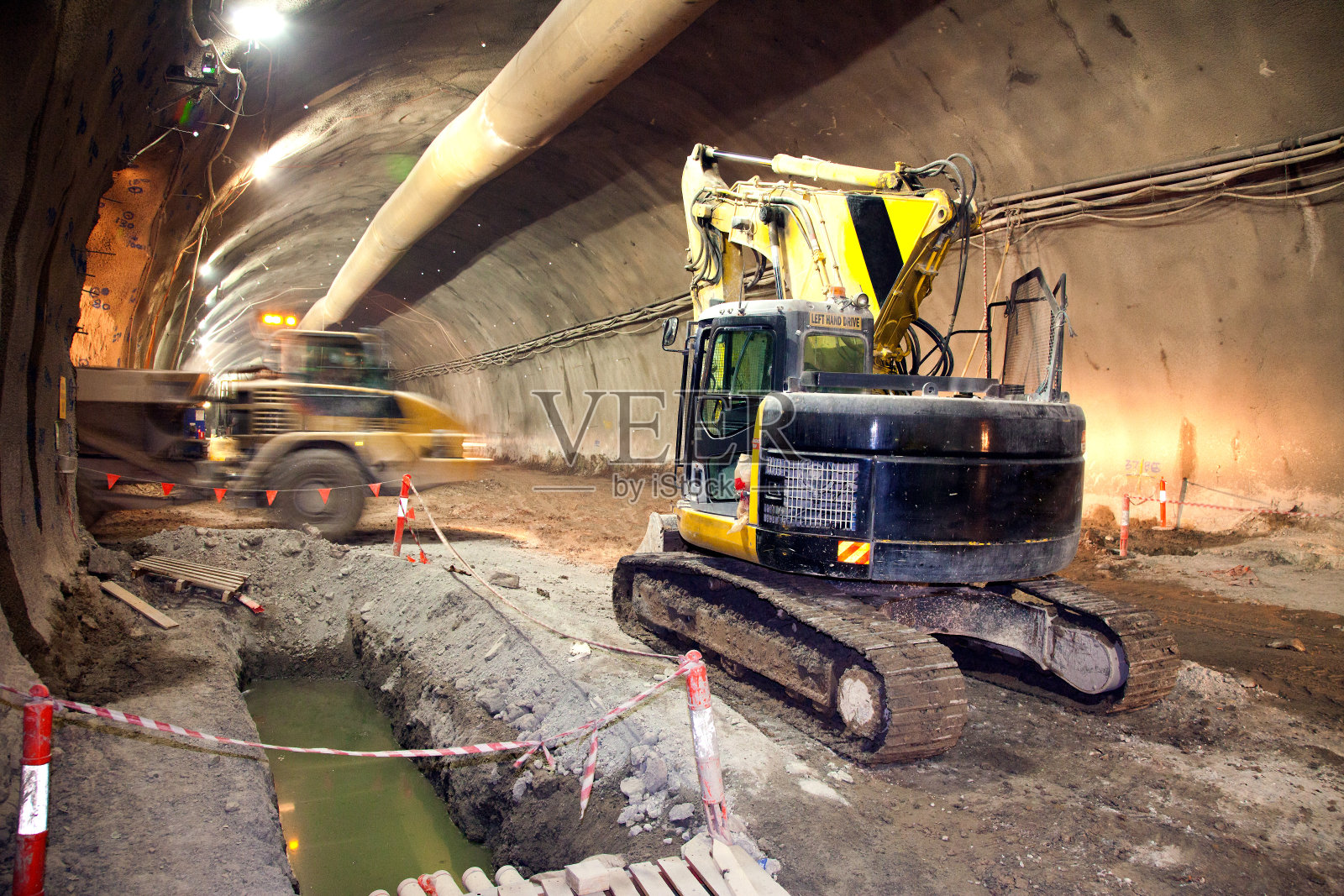 混凝土道路隧道施工挖掘机和自卸车照片摄影图片
