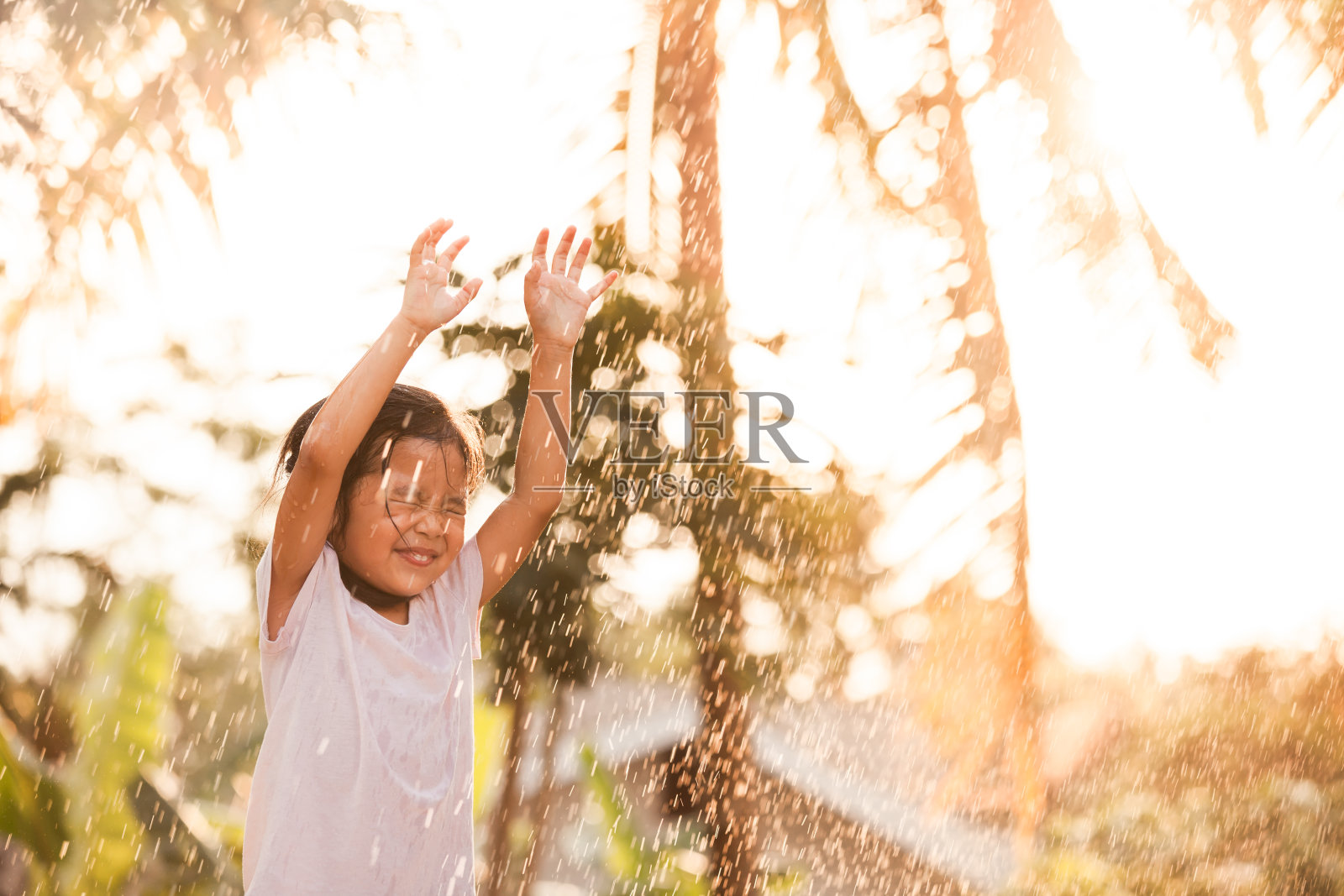 快乐的亚洲小女孩玩雨的乐趣照片摄影图片