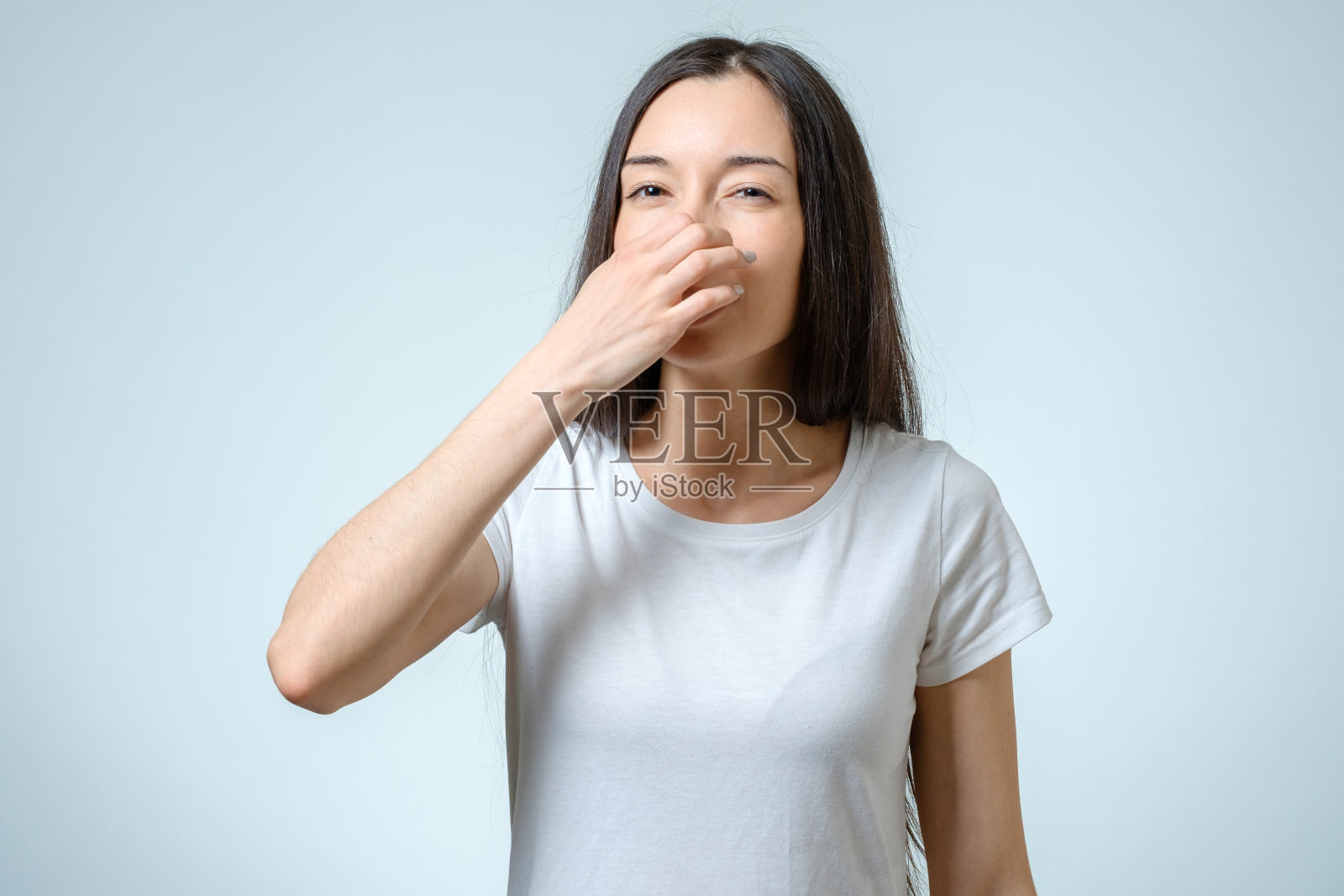 女孩用手捂住鼻子，表明灰色背景上有孤立的臭气照片摄影图片